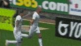 two soccer players are running on a field in front of a bob.com ad