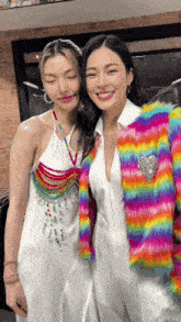 two women are posing for a picture and one is wearing a colorful jacket