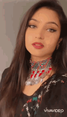 a woman is wearing a choker necklace and earrings and is being filmed with vivavideo