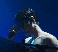 a man without a shirt is holding a microphone