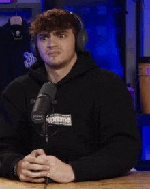 a man wearing headphones and a black supreme sweatshirt