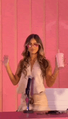 a woman is dancing in front of a microphone while holding a cup of soda .