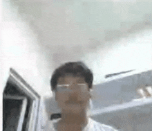 a man wearing glasses is standing in a hallway in front of a door .