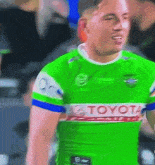 a man wearing a green toyota jersey stands in front of a crowd