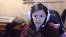 a woman wearing headphones and a microphone is sitting in a gaming chair .