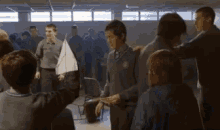 a group of people are standing in a circle with a boy holding a sailboat