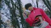 a man in a pink hoodie has a purple object in his hand