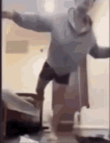 a man is standing on one leg in a room in front of a bed .