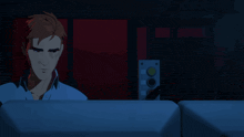 a man in a blue shirt sits in a dark room with a red background