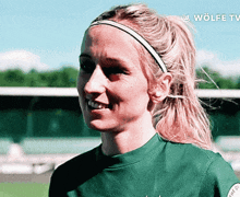 a woman wearing a headband and a green shirt with the word wolfe tv on the bottom