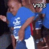 a man in a blue shirt with the number 103 on the bottom right