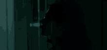a person is peeking out of a dark room through a doorway .