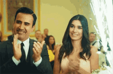 a man in a suit and tie is clapping with a woman in a dress