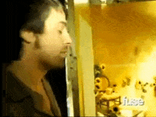 a man with a beard is standing in front of a door in a room with stuffed animals on the wall .