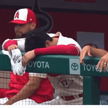 a baseball player leans on a toyota fence