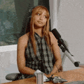 a woman wearing headphones sits at a table with a microphone