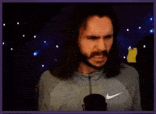 a man with a beard is standing in front of a microphone .