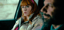 a woman with red hair is sitting next to a man in a car with haynah written on the bottom