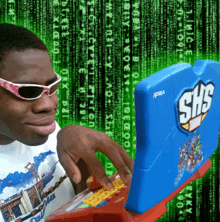 a boy wearing sunglasses is typing on a shs marvel laptop