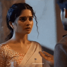 a woman in a white sari is talking to a man in a suit