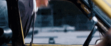 a man in a suit is driving a yellow car