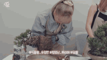 a woman is working on a potted plant with a bag of dirt in the background