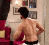 a shirtless man standing in front of a punching bag
