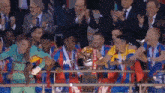 a soccer team is holding a trophy in front of a crowd of people .