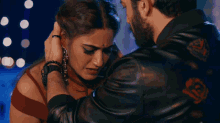 a man with a beard is touching a woman 's head with his hand