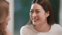 a woman is smiling and looking at another woman 's face .