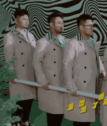 a group of men in trench coats are holding swords in front of a striped background