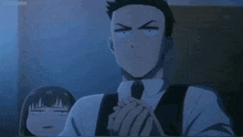 a man in a suit and tie is sitting at a table with his hands folded in front of a woman .