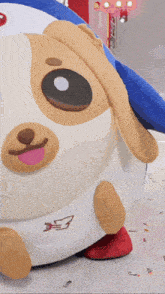 a stuffed animal that looks like a dog with a blue hat on