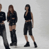 three women are standing next to each other on a white background . one of the women is wearing a black crop top .