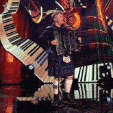a man in a kilt is playing an accordion in front of a piano