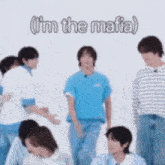 a group of young men are standing next to each other in front of a white wall and one of them is pointing at the camera .