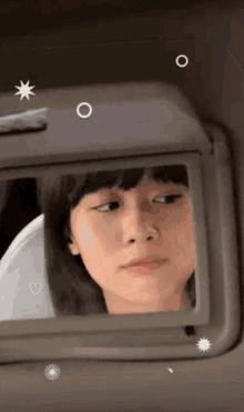 a girl is looking at herself in a visor mirror