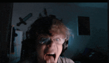 a boy wearing glasses and headphones sticking out his tongue