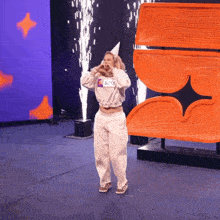 a woman wearing a sweatshirt that says ' stars ' on it stands on a stage
