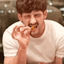 a man with a mustache is eating a piece of food with his hands .