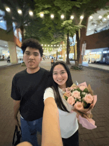 a man holds a bouquet of pink roses while standing next to a woman