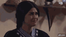 a woman is crying while wearing a striped shirt and earrings .