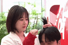 a woman in a white coat with the word dr. on it brushes a man 's hair