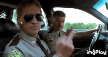 two police officers are sitting in a car and one of them is giving the middle finger .