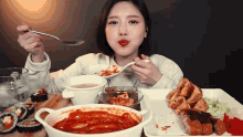 a woman is sitting at a table eating food with a spoon in her mouth