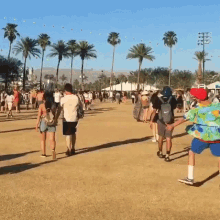 a group of people are walking down a dirt road