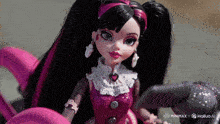 a doll with black and pink hair and a heart necklace is sitting in front of a sign that says minimax