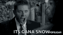 a black and white photo of a man in a suit and tie with his mouth open and the words `` it 's gana snow '' .