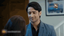 a man in a suit and black shirt is looking at a woman in a room .