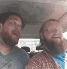 two men are sitting in the back seat of a car .
